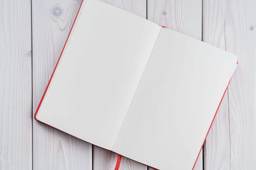 Red diary, text book with white paper pages on wooden table background. Making notes in empty workbook on office desk. Personal organizer as reminder. Blank and template. Copy space, flat lay