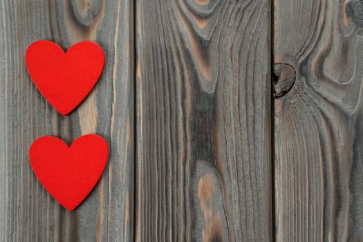 Small red hearts dancing and moving in the circle on dark wood background. Saint valentines day, 14 February love card greetings. Memory handmade, craft present from the heart. Copy space, top view