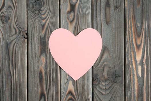 Pink paper heart on dark wooden plank background. Falling in love and confession in saint valentines day. Be my valentine. Love message and romantic holiday celebration. Mockup, copy space, flat lay