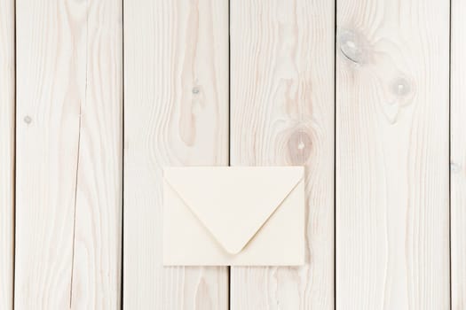 White craft handmade closed paper envelope laying on white wooden plank background. Post card message, letter sending. New delivery and retro traditional invitation. Copy space, mockup, flat lay