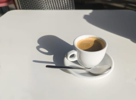 Coffee cup over terrace table a sunny day. Overhead view