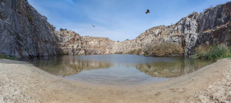Vultures overflying old quarry of Alcantara, now used as natural swimming pool, Caceres, Extremadura, Spain