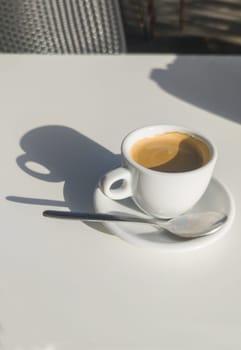 Coffee cup over terrace table a sunny day. Overhead view