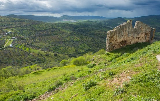 Buiding remains beside Feria castle hill, Spain. Fields of farming with olive trees and typical dehesa pastoral management fields.