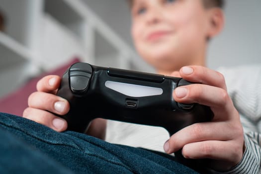 Hands of boy hold modified plastic joystick closeup, selective focus. Child play videogames. Hold wireless black game console. Hobby of teenager, lifestyle. Modern technologies and gaming.