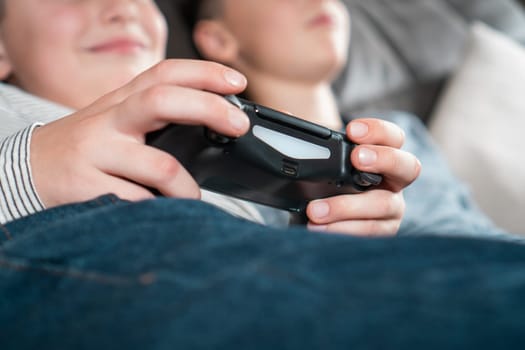 Hands of boy hold modified plastic joystick closeup, selective focus. Children play videogames. Hold wireless black game console. Hobby of teenager, lifestyle. Modern technologies and gaming.