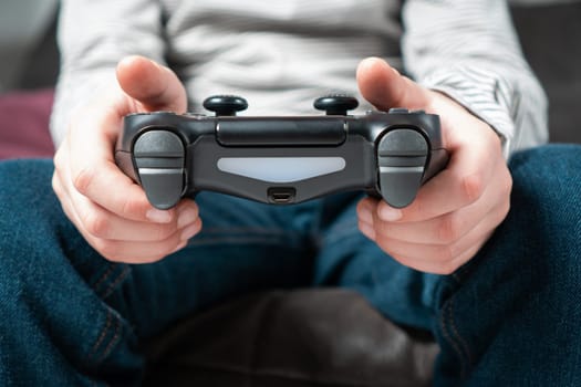 Male hands hold modified plastic joystick closeup, selective focus. Person play videogames. Hold wireless game console. Press buttons on controller by fingers. Modern technologies and gaming.