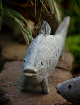 The sculpture, figure of a fish on the edge of my goldfish pond.