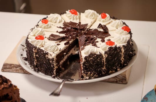 A cut chocolate cream cake with pieces already missing.