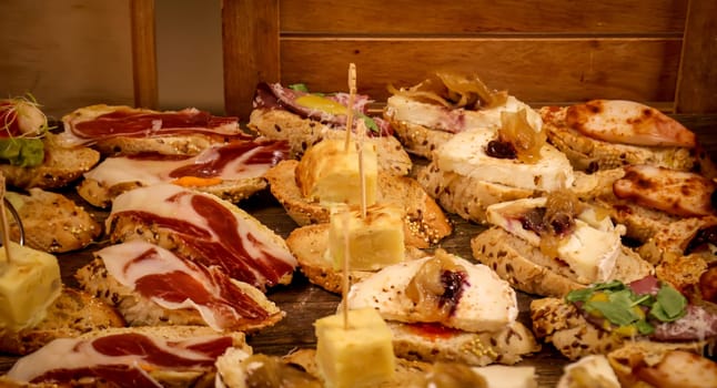 Many bites with cheese and ham in a tapas bar.