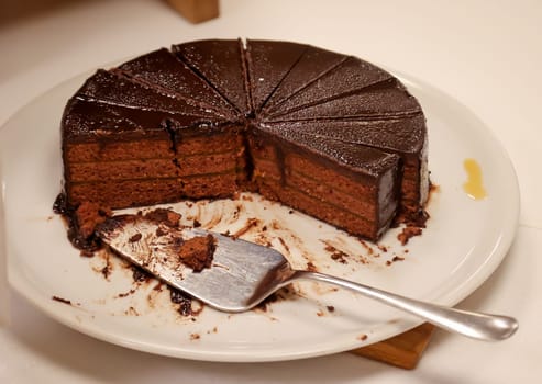 A cut chocolate cream cake with pieces already missing.