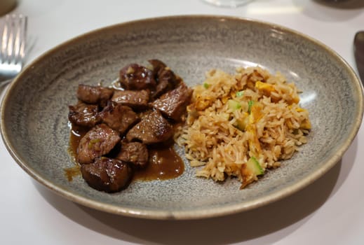 Cut up well prepared fillet of beef with rice and vegetables on a plate.