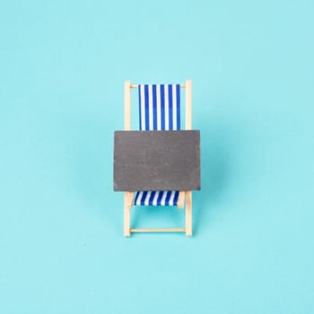 Lounge chair with a blank chalkboard sign, summer vacation travel by the sea