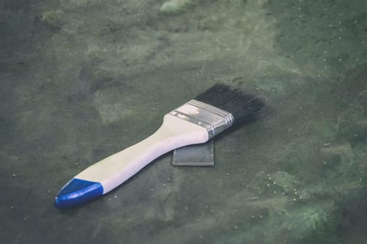White paint brush on the gray-black cement floor