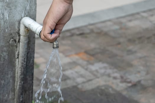 Old faucet and hand are open water.