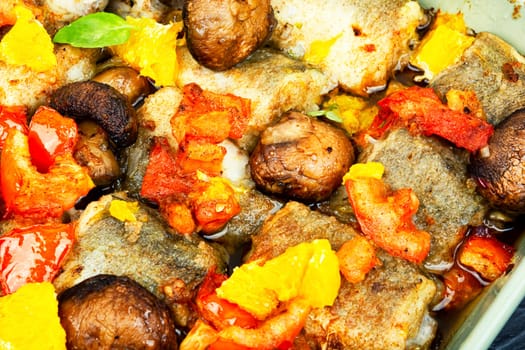 Diet fish hake cooked with mushrooms, orange and tomatoes. Food background, close up