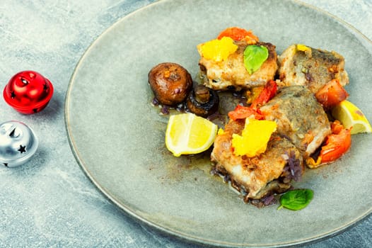Diet fish hake cooked with mushrooms, orange and tomatoes. Food background, close up