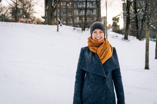 A young woman in winter clothes smiles broadly looking into the camera.