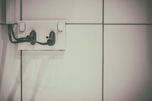 The old electrical plug next to the cream wall.