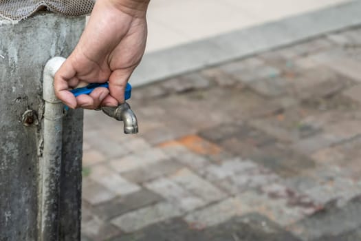 Old faucet and hand are open water.