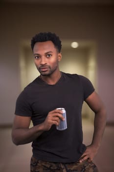 cool attitude man drinking soda holding can cola in hand wearing black t-shirt indoor