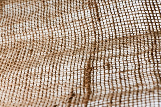 Full-frame view of coarse textile fabric with sharpness gradient on a white backlit background.