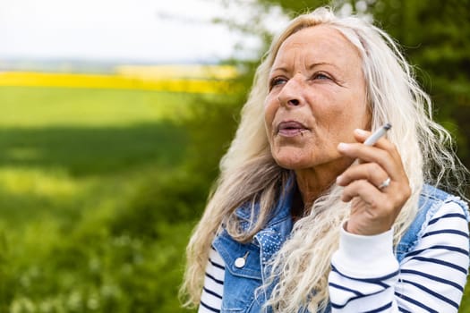 Portrait from a Lady smoking outdoor a cigarette.