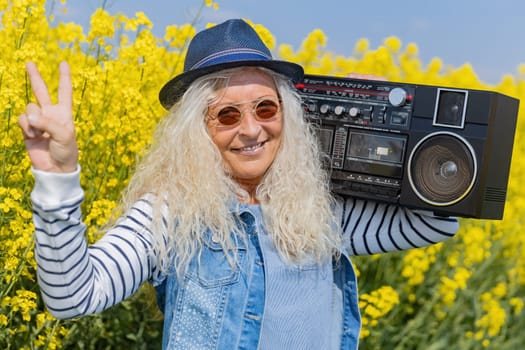 Elderly Woman have fun with vintage Boom Box in Nature.