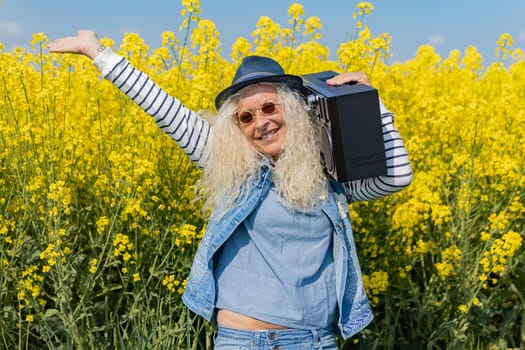 Elderly Woman with piercing have fun with vintage Boom Box in Nature.