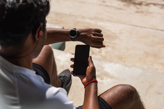 Close up Asian young athlete sport runner black man wear modern time smart watch and sync to a smartphone check running result after a training run at the outdoor, healthy exercise workout technology