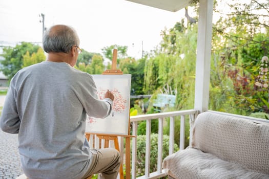 Lifestyle elderly people smile paint at his easel outside home, Asian senior old man painting picture using brush and oil color on canvas, Happy retirement artist and activity concept