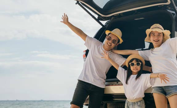 Happy Family Day. People enjoying road trip standing on back their car raise arms and hand up, Father, Mother and daughter traveling at sea beach, small family having fun in summer vacation on beach
