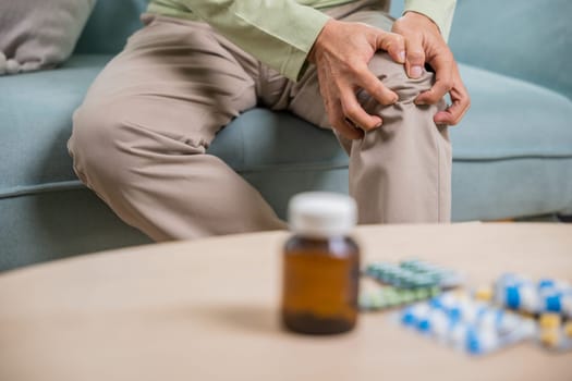 Old age. Asian senior man retirement knee joint pain on sofa, Elderly old man sitting down hands hold knee, Grandfather people health care bone problem at home