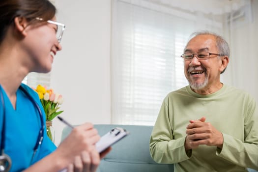 Elderly man takes doctor at home telling about health complaints, Asian young nurse writing prescription clipboard while talking during home visit sick senior old man, Healthcare and medical concept