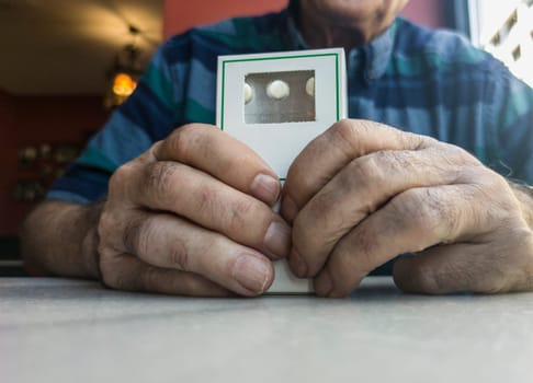 Old man holds a box of pills. Inappropriate use of medication by elderly concept