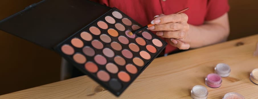 Close-up of woman holding makeup brush and blush and eyeshadow palette - beauty and cosmetics