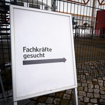 Sign at the entrance of a company premises with the German inscription Fachkrafte gesucht. Translation: Skilled workers wanted