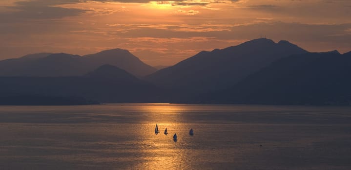 Sunset,evening atmosphere on Lake Garda with sailing boats on the water. Sunset,evening mood at Lake Garda with sailing boats on the water.