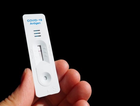 The test result for COVID-19 is negative, not infected, using rapid testing equipment. Test for coronavirus on the hand, black background. Copy space. Testing Concept Coronavirus Disease infection