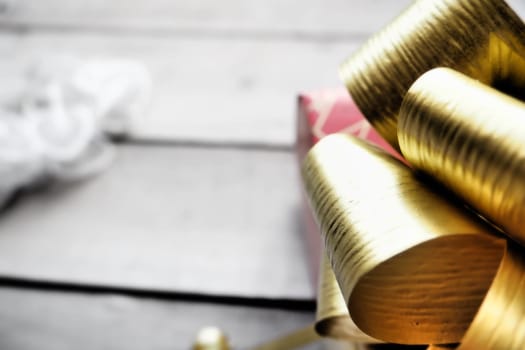 Red gift box with a large gold bow on a wooden background painted with white paint. Gift for Christmas, New Year, Birthday, Mother's Day, Wedding, Valentine's Day. Beautiful festive decoration.