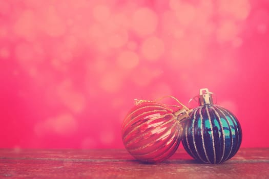 Christmas balls on a red-pink background. Glare bokeh. New Year or Christmas card. Red and blue Christmas decorations for the holiday. Copy space.