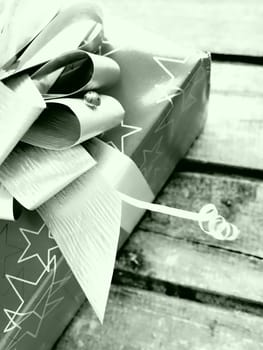 Gift box with a large bow on a wooden background. Gift for Christmas, New Year, Birthday, Mother's Day, Wedding, Valentine's Day. Beautiful festive decoration. Give gifts. Green tint. White and black