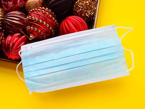 Protective surgical mask on a box with Christmas decorations. Covid New Year. Holiday restrictions and lockdown concept. Corona virus epidemic covid-19.