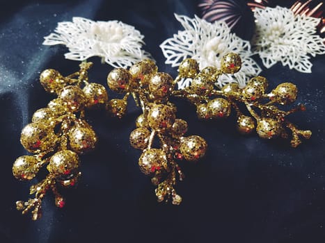 card for the new year and christmas with decorations, Christmas decorations and sparkles on a black background. Shiny white flowers and snowflakes, golden twigs with berries. Blue haze. Soft focus.
