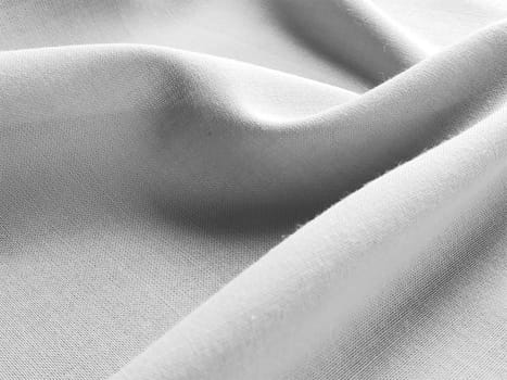 Beautifully folded fabric. Soft pleasant waves and flounces on textiles. Close-up. Drapery for curtains, fabric for dressmaking or upholstery. Black and white monochrome image.