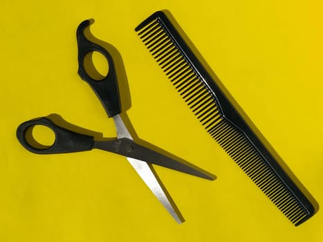 Hairdressing scissors and combs on a yellow background with space for text. Tools of a professional hairdresser. Beauty saloon. Hairdressing equipment.