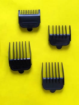 Nozzles for hair clippers. Plastic combs for trimmer. Yellow background. Four subjects. Hairdresser tools. Hairdressing and beauty salon equipment.