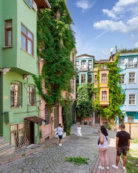 Istanbul, Turkey - August 28, 2022: Tourists taking memorial photos in front of traditional colorful old houses in old Balat district, in a summer day