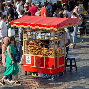 Istanbul, Turkey - August 30, 2022: Male peddler selling simit, on traditional Turkish fast food cart at Eminonu Piazza