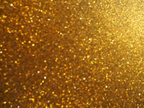 Bokeh light of gold glitters. Golden glitter texture background. Sparkling glitter wrapping paper with sequins and sparkles. Festive golden bokeh and glitter. Beautiful macro background.